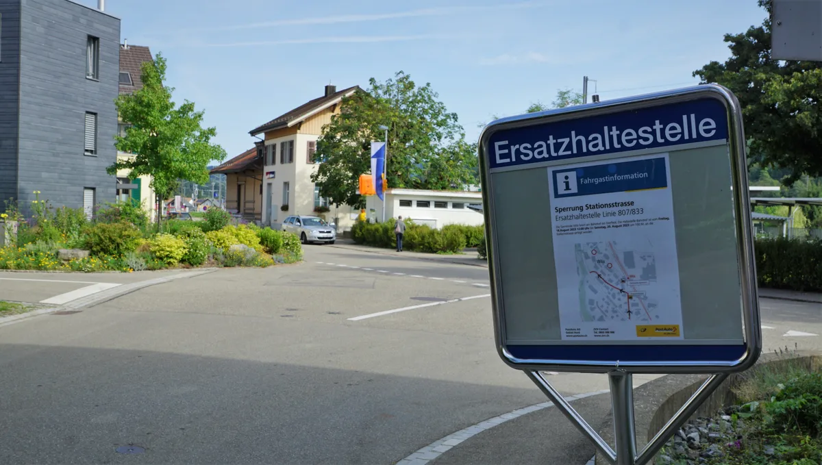 Man sieht eine Haltestelle-Tafel an einer Strasse.