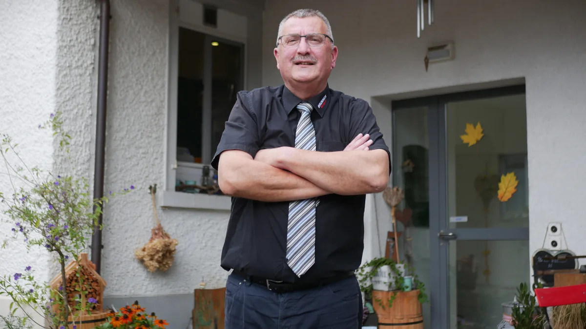 Man sieht einen Mann mit Hemd und Krawatte, der seine Arme verschränkt.