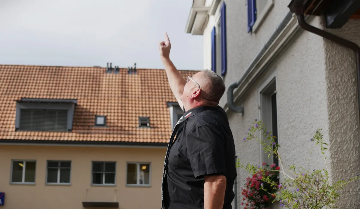 Man sieht einen Mann mit Hemd und Krawatte, der mit seinem Arm in den Himmel deutet.