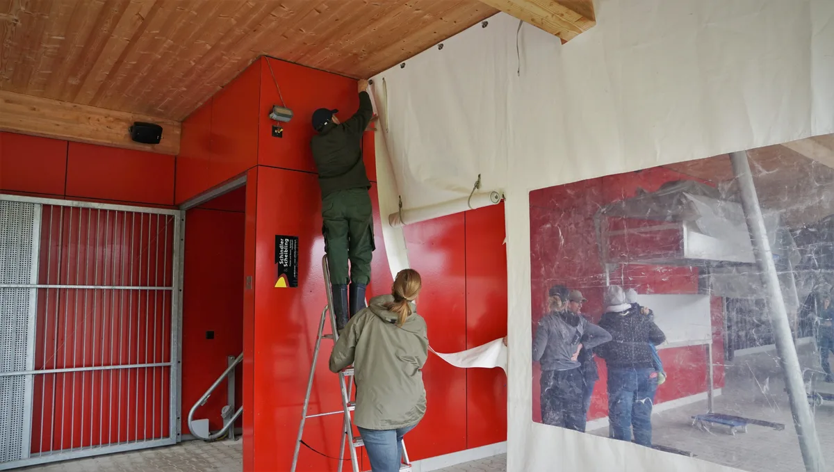 Man sieht einen Mann der auf  einer Leiter steht und ein Banner montiert.