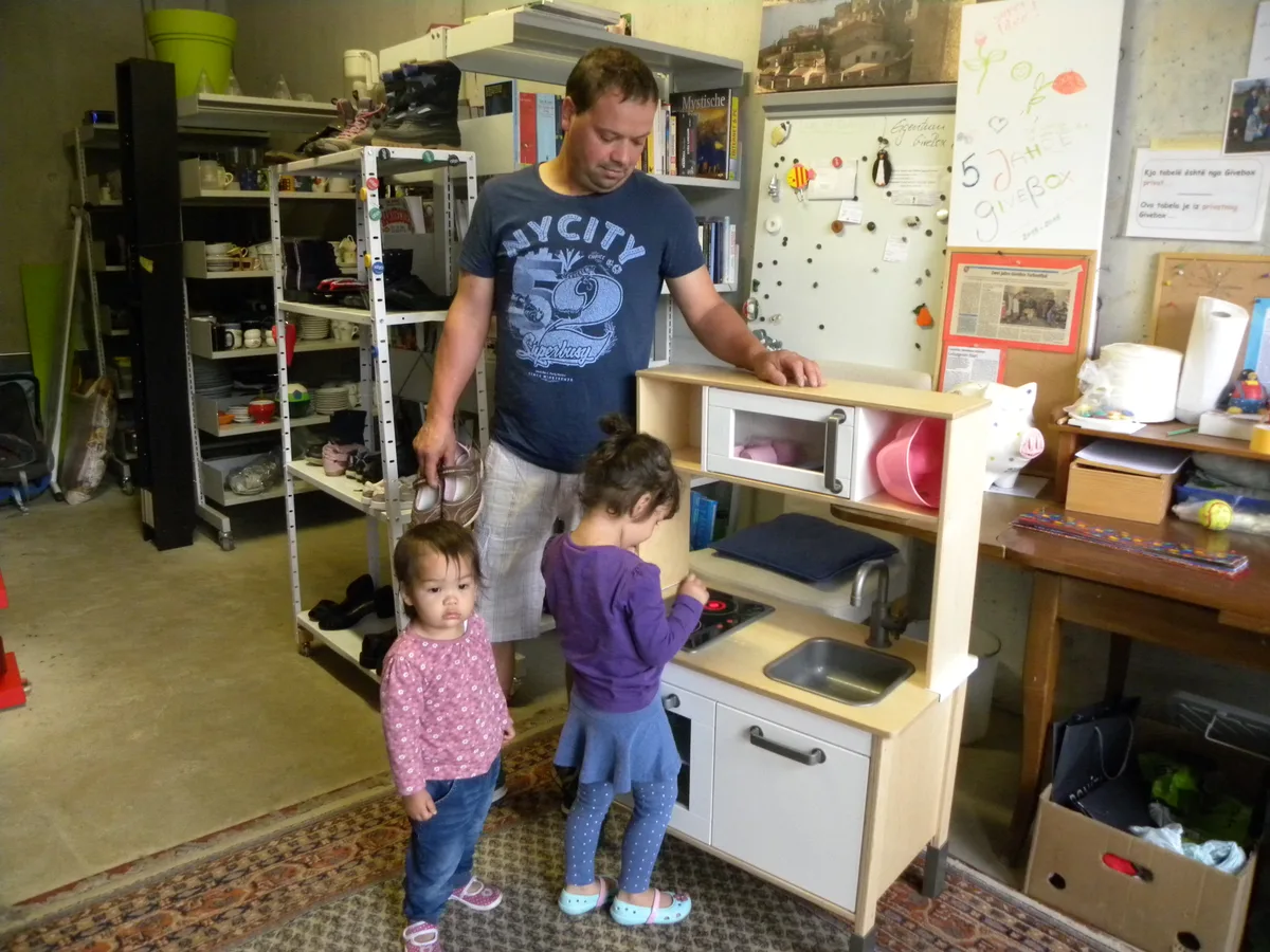 Man sieht Vater und Kinder, die eine Spielzeugkücke anschauen.