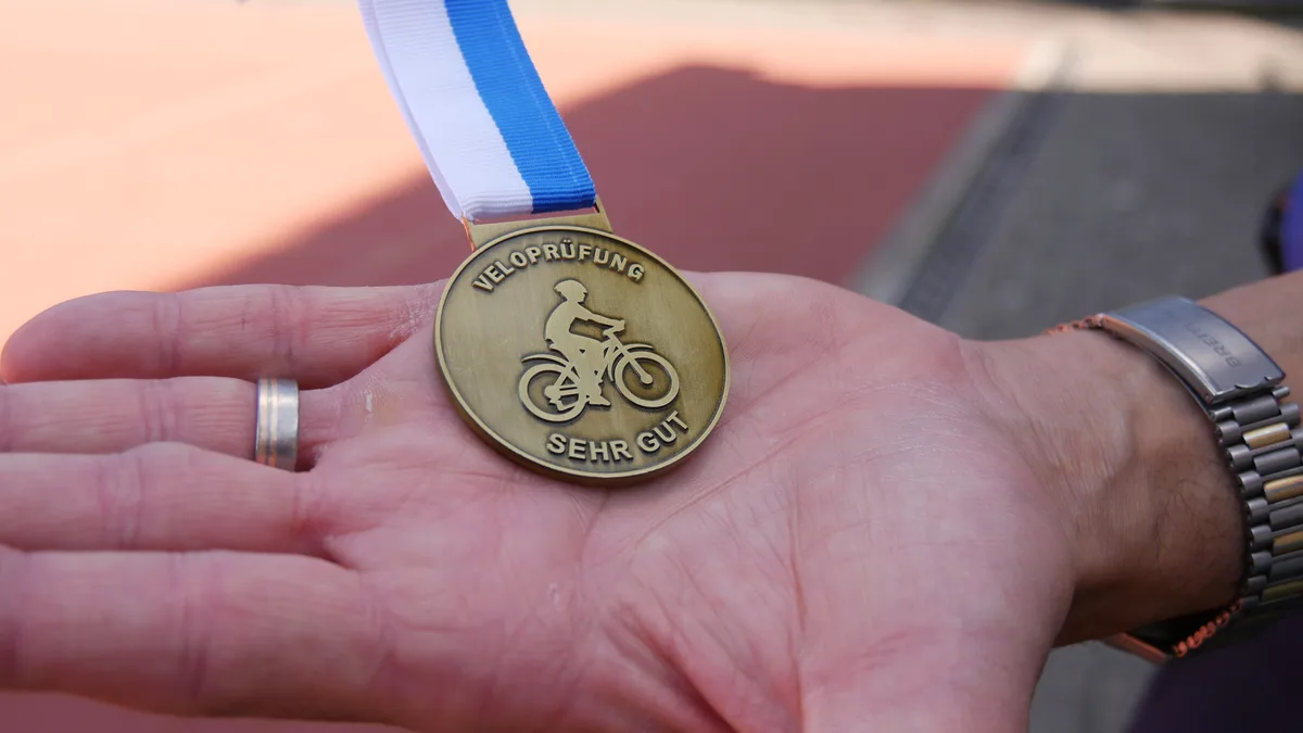 Medaille mit der Aufschrift «Veloprüfung – sehr gut».