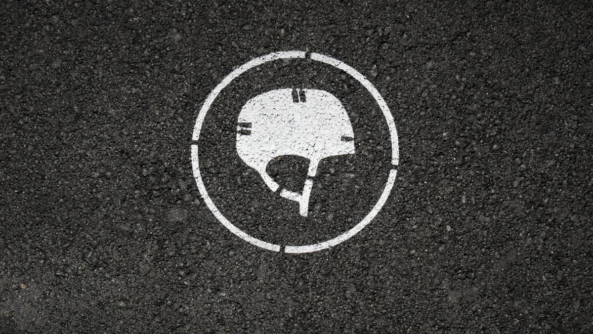 Man sieht ein auf den Asphalt gespraytes Symbol eines Skater-Helms.