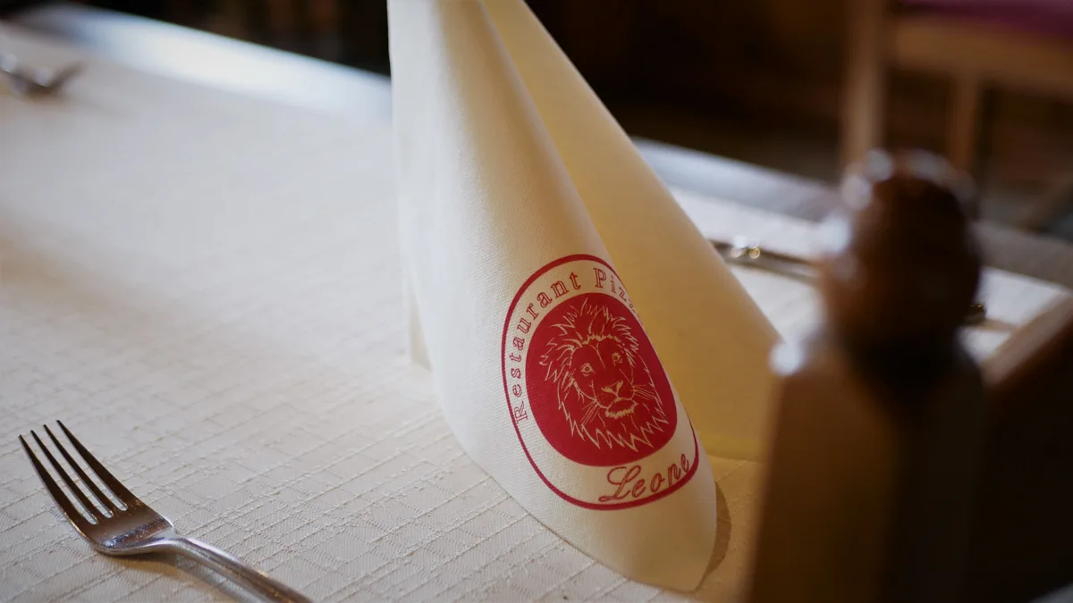 Man sieht ein Tischgedeck mit dem Namen des Restaurants auf der Serviette.