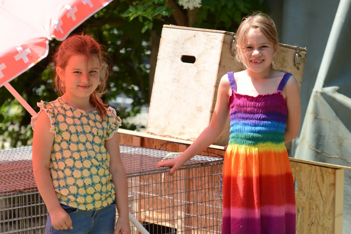 Das sind Lucy und Louisa… Zwei Mädchen stehen vor einem Käfig.