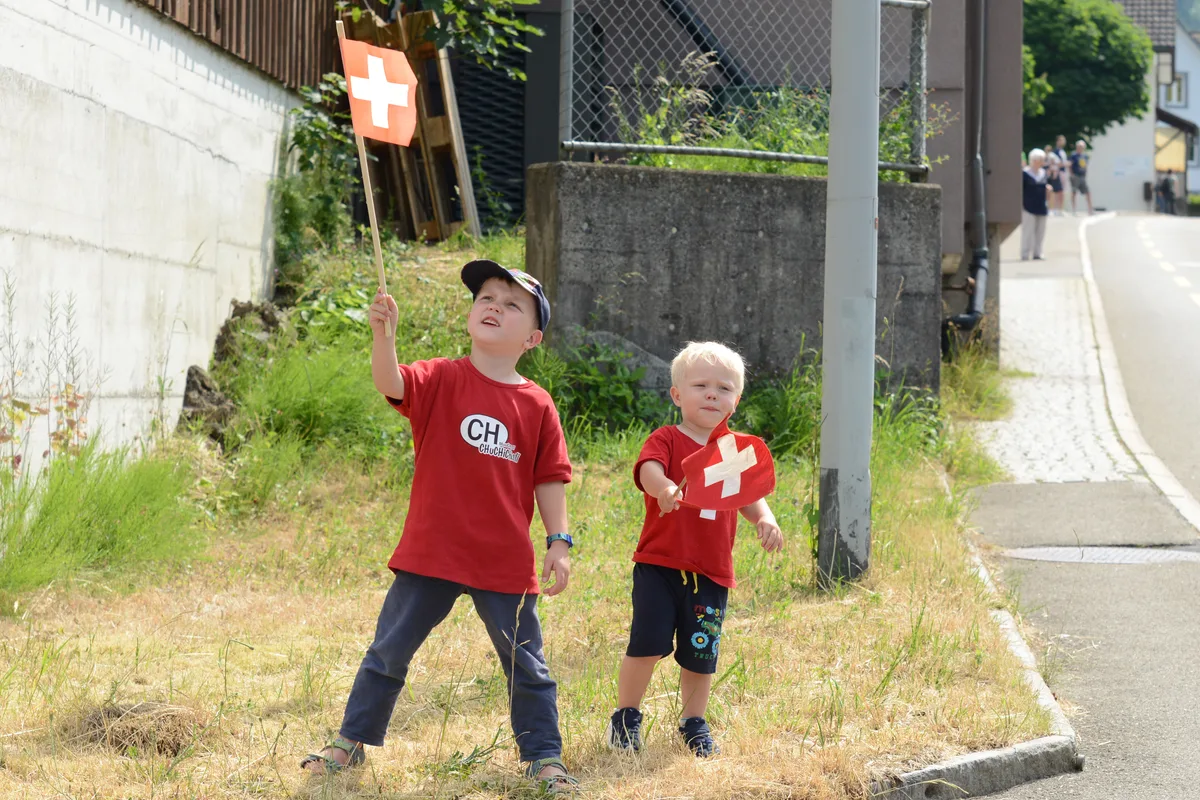 Finn und Tamo Knobel feuern alle Fahrerinnen an. Zwei Kinder in Schweiz-Montur.