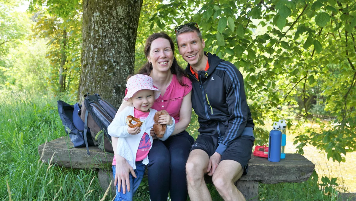 Man sieht eine Familie, die auf einem Baumstamm sitzt.