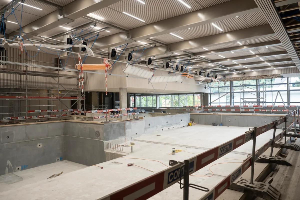 Obwohl es noch viel zu tun gibt, nimmt das Bad Form an. An der Decke ist bereits der neue Seilgarten montiert. Blick auf die Baustelle: Man sieht die Halle mit Schwimmbecken.