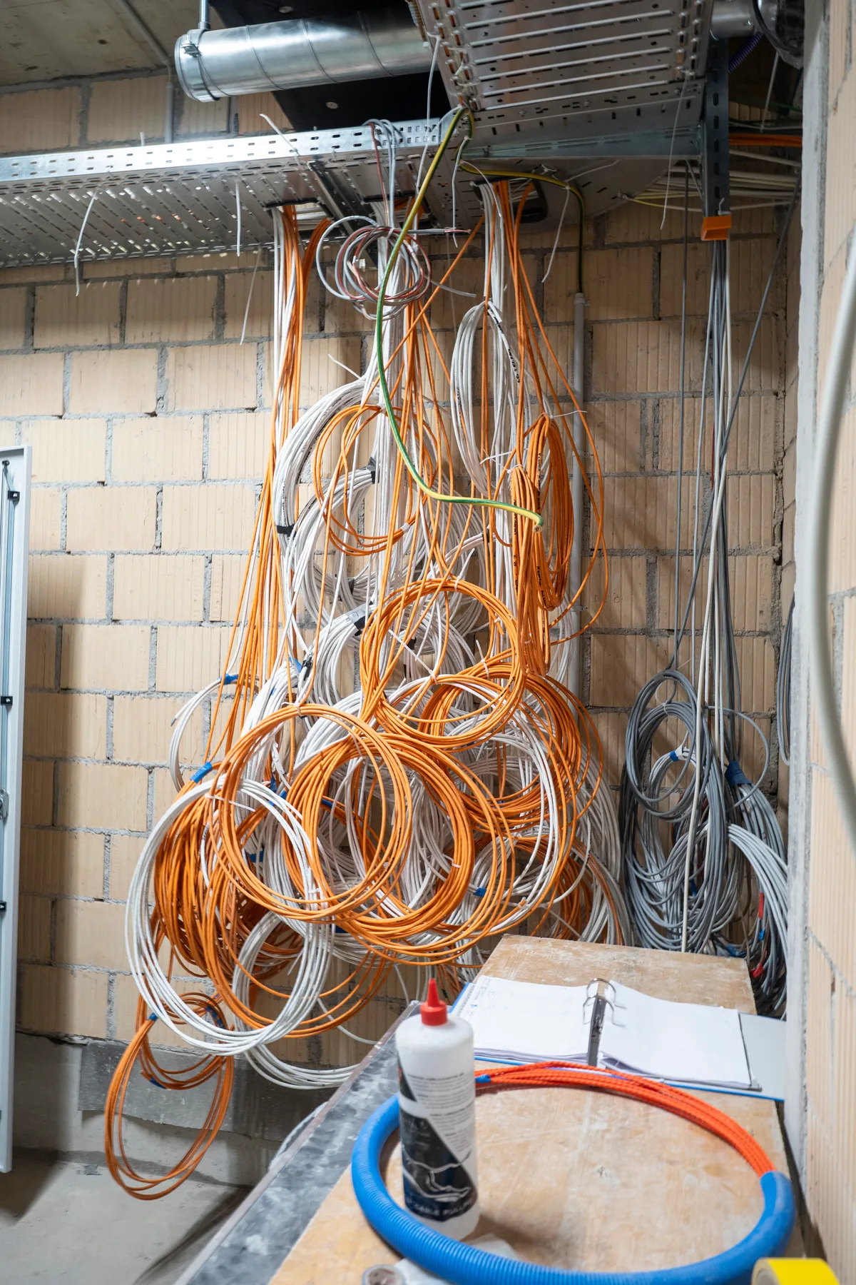 Überall sind noch Kabel sichtbar, die auf ihren Verwendungszweck warten. Blick auf die Baustelle: Man sieht Kabel, die von der Decke hängen.