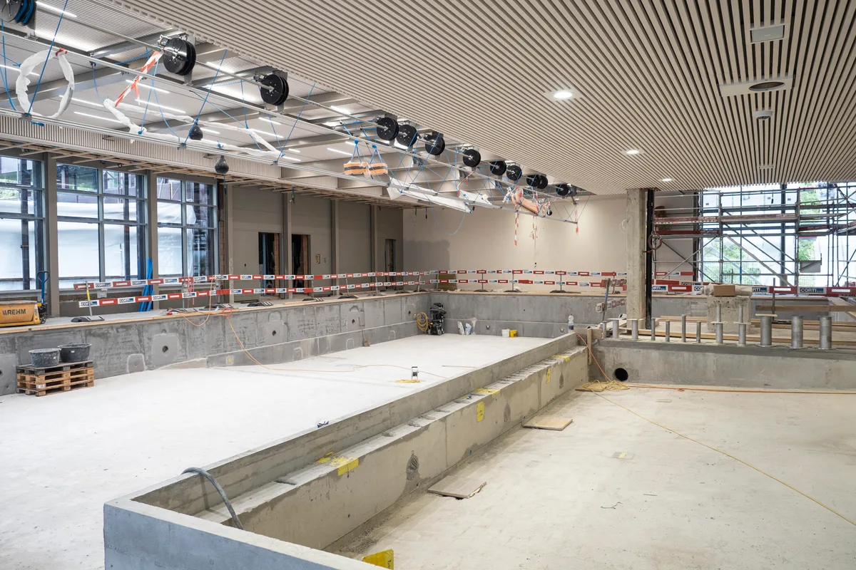 Das Nichtschwimmerbecken ist neu mit einer Wand vom Schwimmbecken abgetrennt. Blick auf die Baustelle: Man sieht die Halle mit Schwimmbecken.