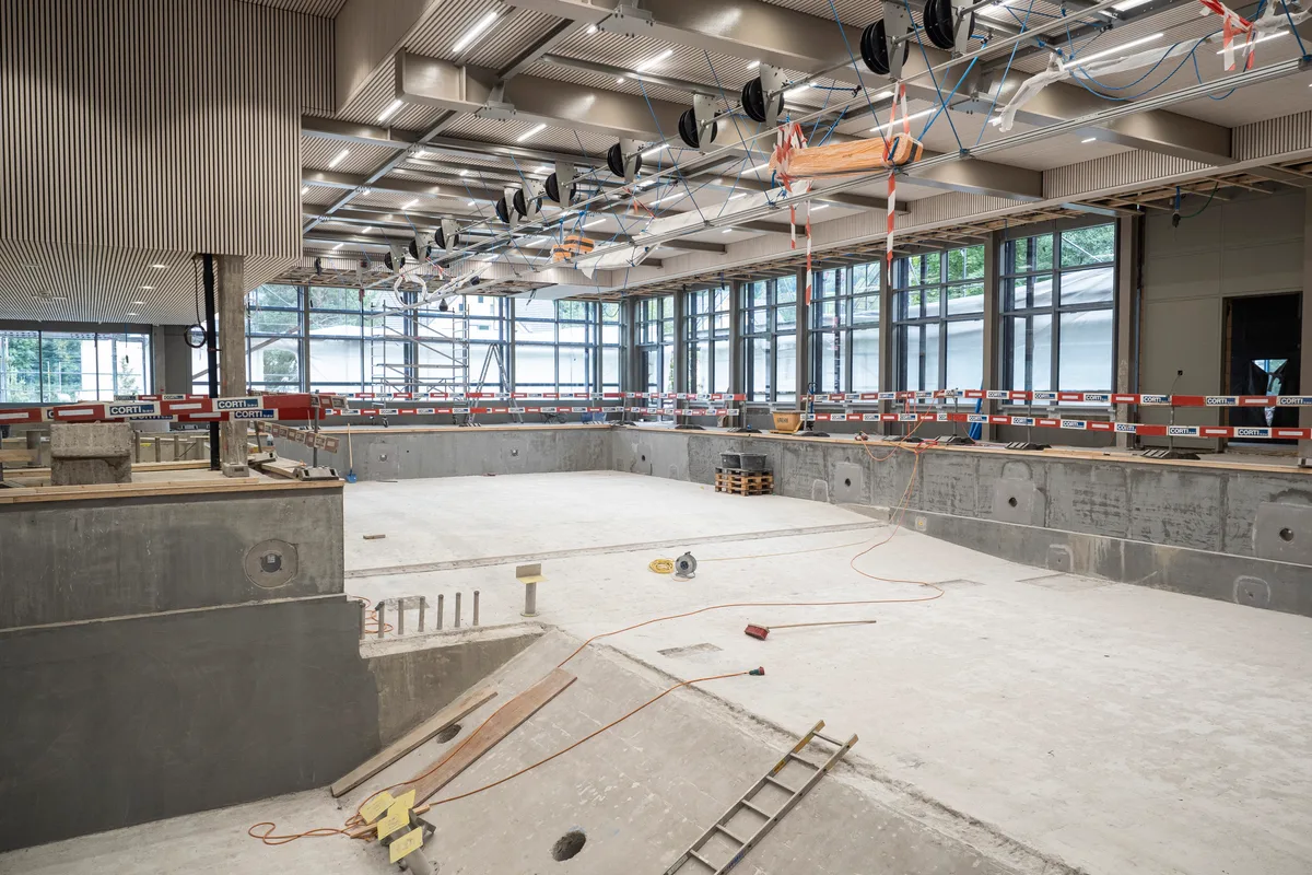 An der Form des bestehenden Schwimmbeckens wurde nichts verändert. Blick auf die Baustelle: Man sieht die Halle mit Schwimmbecken.