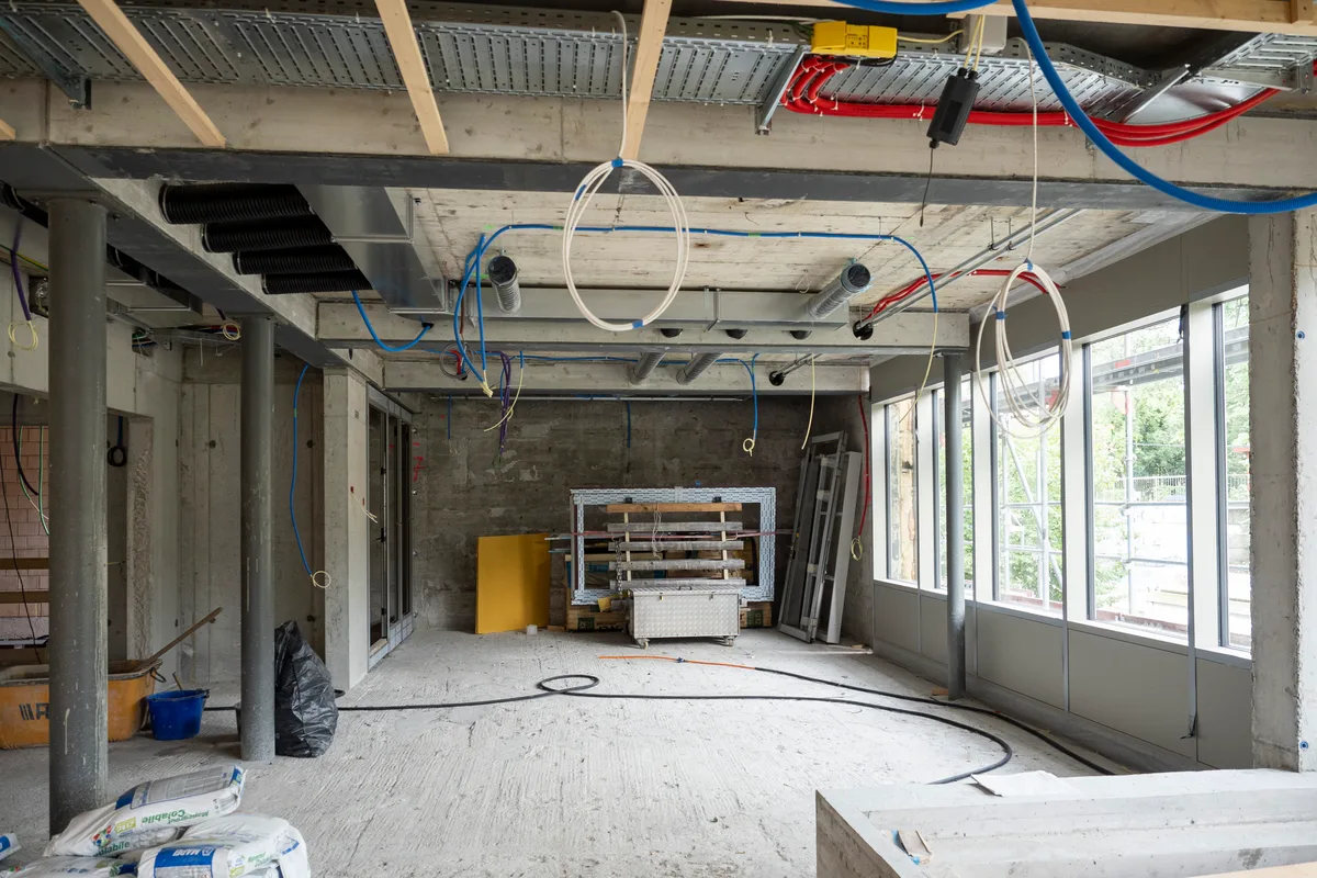 Noch braucht es viel Phantasie, um sich das Bistro, das hier entsteht, vorstellen zu können. Blick auf die Baustelle: Man sieht einen noch leeren Raum mit einer Fensterfront.