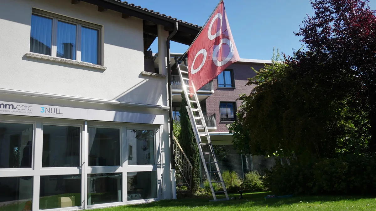 Eine rot-weisse Fahne hängt an einem Gebäude.