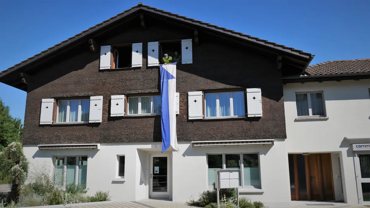 Eine blau-weisse Fahne hängt an einem Gebäude.