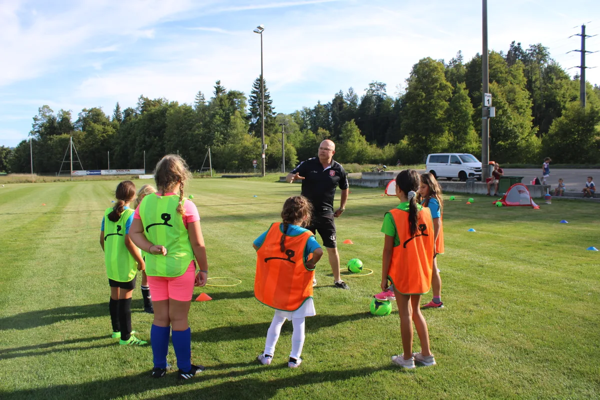 Auf dem Foto sieht man Spielerinnen eines Juniorenfussballteams, die ihrem Trainer zuhören.