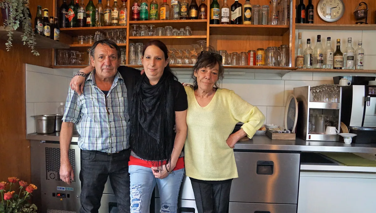 Man sieht zwei Frauen und einen Mann vor einer Theke in einem Restaurant.