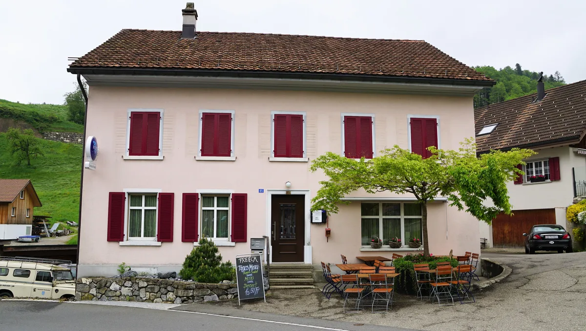 Man sieht ein rosafarbenes Gasthaus.