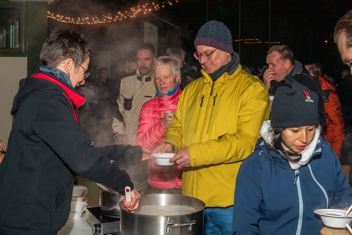 Man sieht Personen, die Suppe abholen.