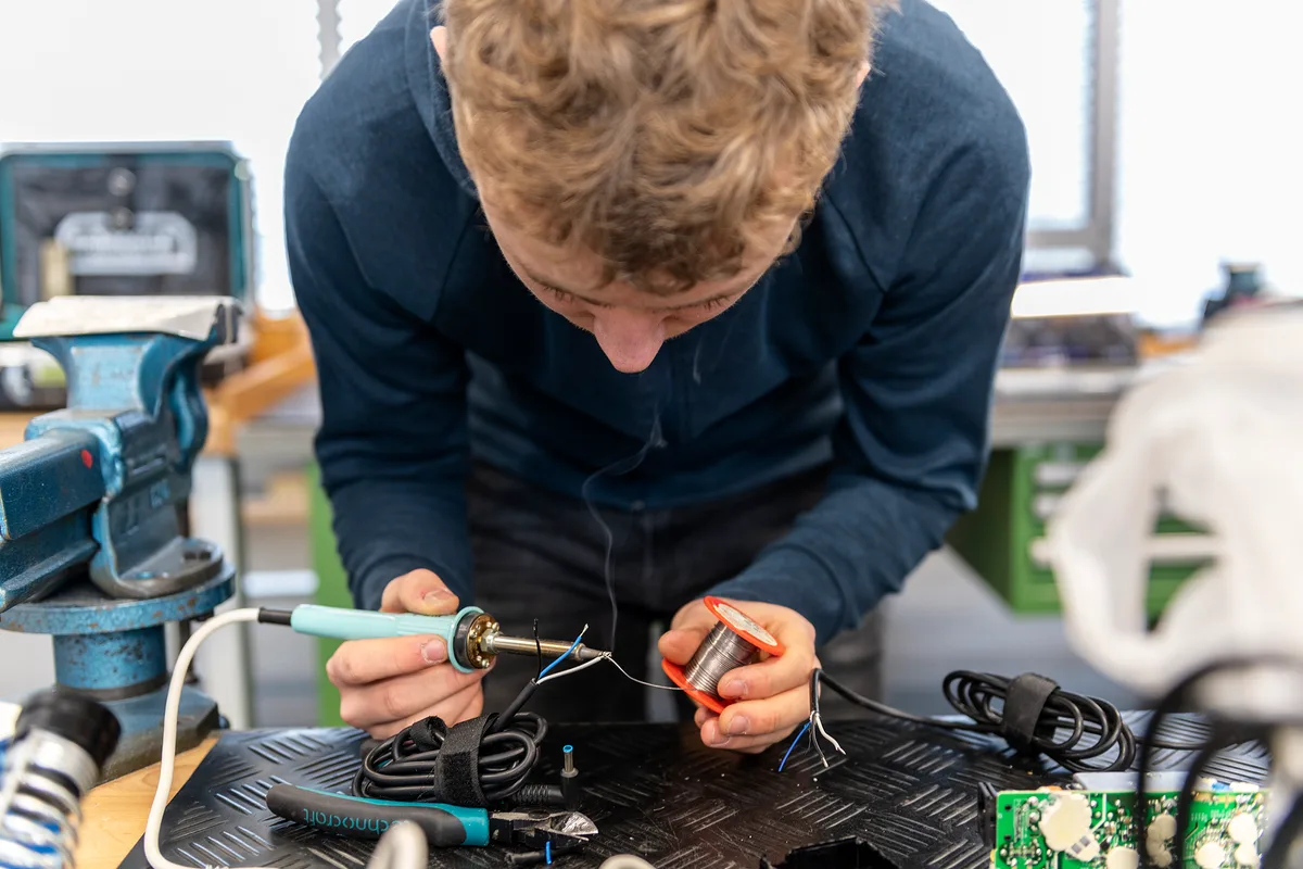 Noah Tabord lötet ein neues Kabel an ein Computer Netzteil. Im Sommer beginnt er seine Lehre als Velomechaniker. Jeden ersten Samstag im Monat wird die Oberstufen-Schul-Werkstatt in Turbenthal zum Repair-Café.