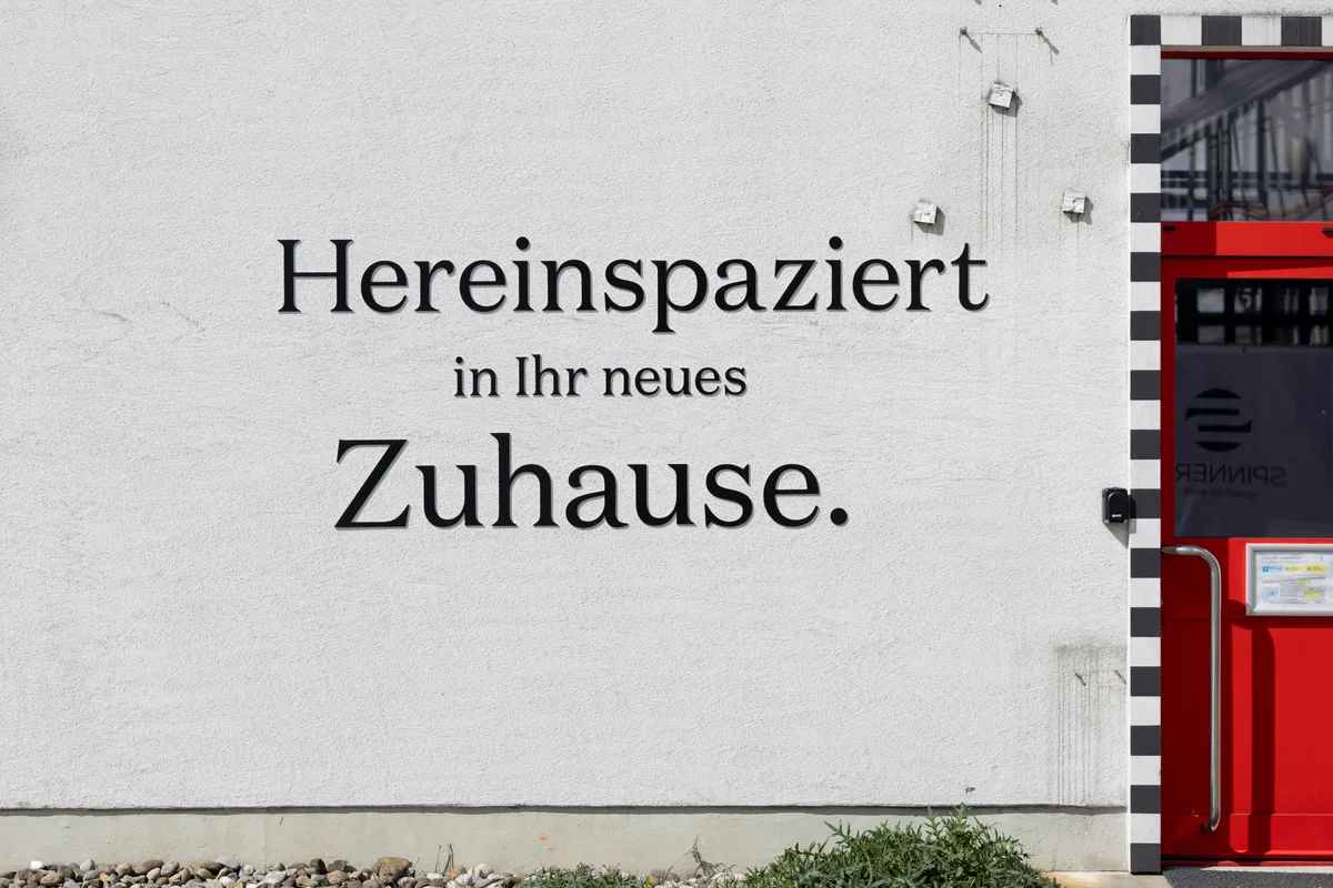 Man sieht die Aussenwand einer Halle mit einem Slogan auf der Wand.