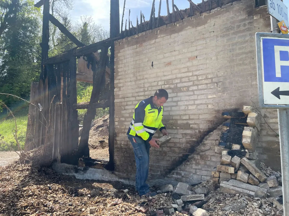 Man sieht, wie der Feuerwehrkommandant sich eine Brandruine genau anschaut.