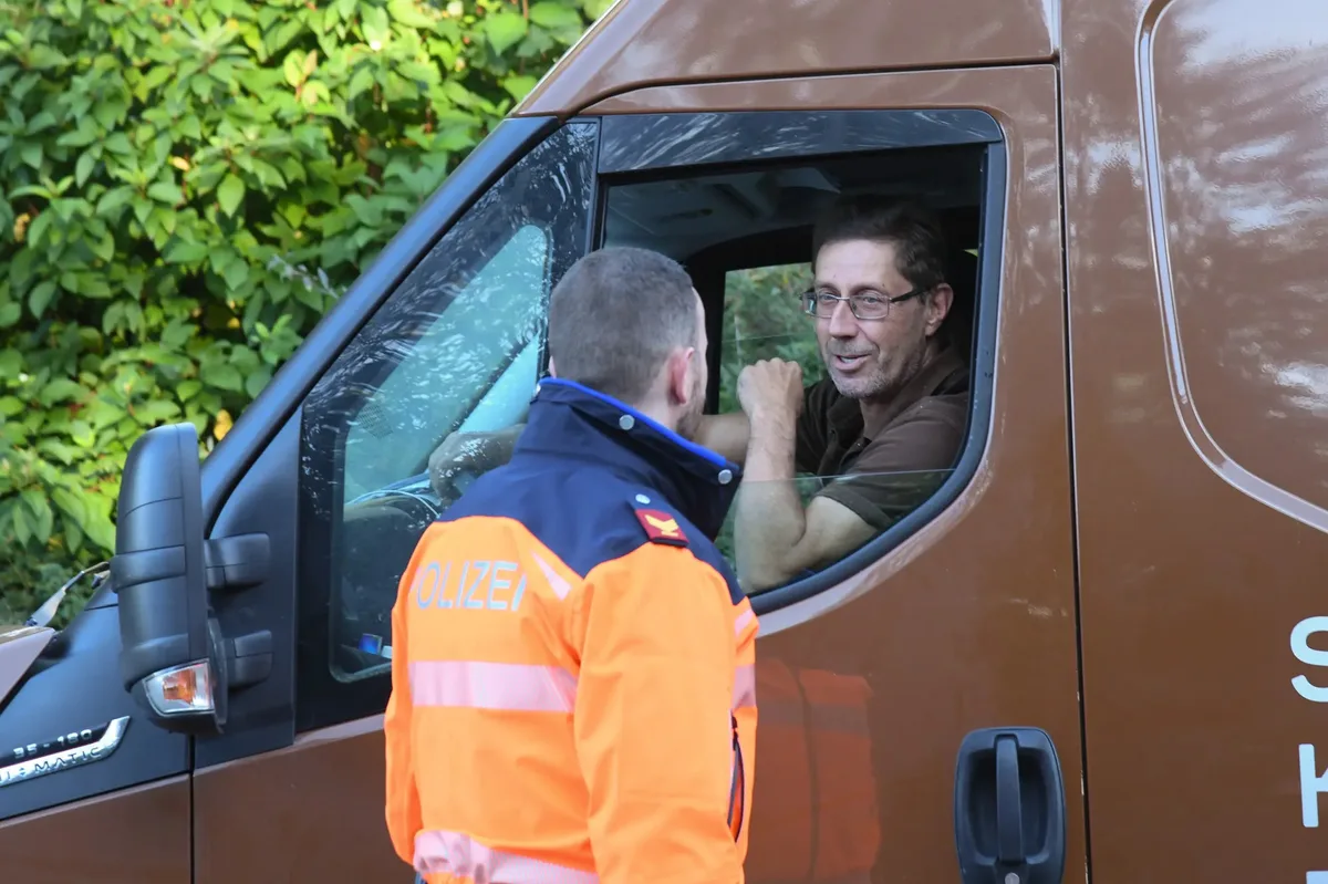 Ein Mann im Fahrzeug spricht mit einem Polizist.