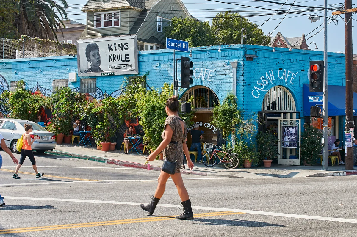 Eine Strasse in Los Angeles mit bunten Häusern, vielen Pflanzen in Blumentöpfen und Menschen in Sommerbekleidung.