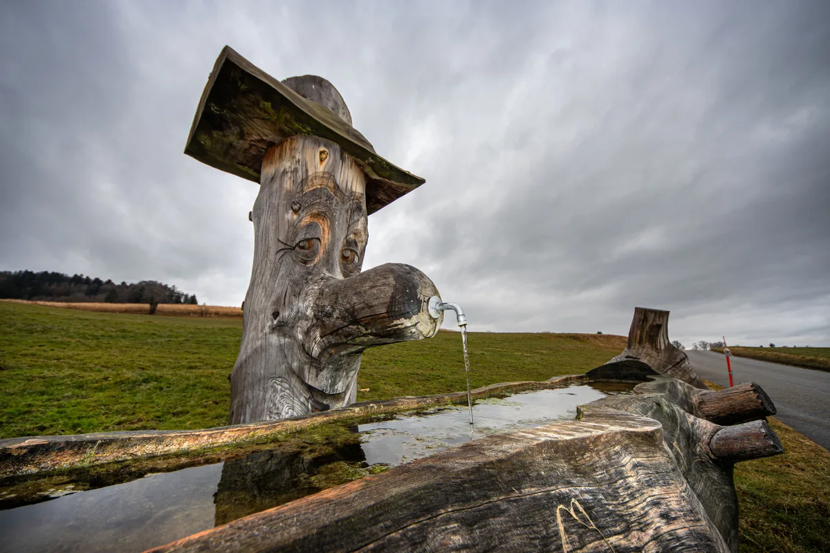 Regenpause über der Ludetswilerstrasse, Neschwil am 6. Februar um 14: 08 Uhr. Beim Brunnen, geschnitzt aus einer alten Fichte von Landwirt Martin Scherz. Die Fichte sei im Frühjahr von Stürmen weggefegt worden.