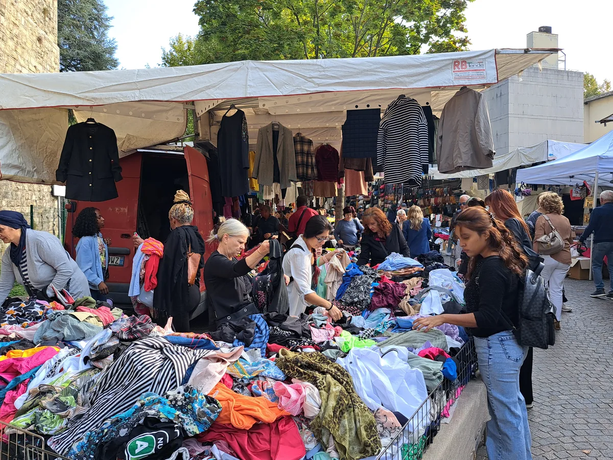 Comos Wochenmarkt ist nicht nur bei den Touristen, sondern auch bei vielen Einheimischen beliebt. Personen, die in Kleiderhaufen wühlen.