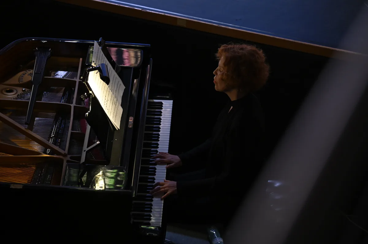 Man sieht eine Frau an einem Klavier spielen,