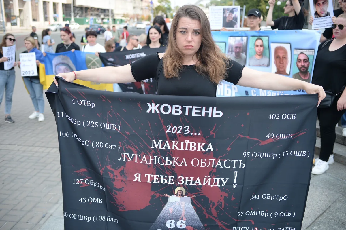 Eine junge ukrainische Frau mit einem Transparent in der Hand. Sie schaut verzweifelt.