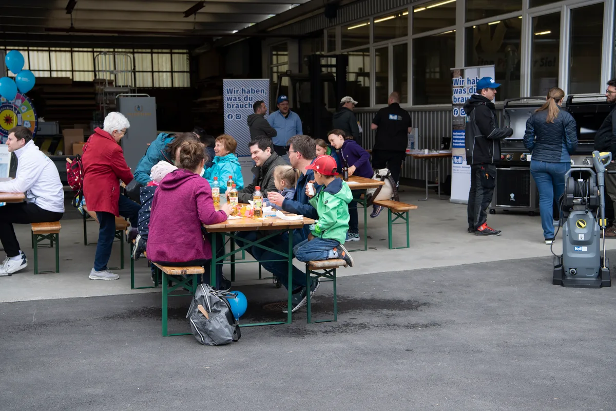 Personen sitzen an einem Holztisch und essen. 