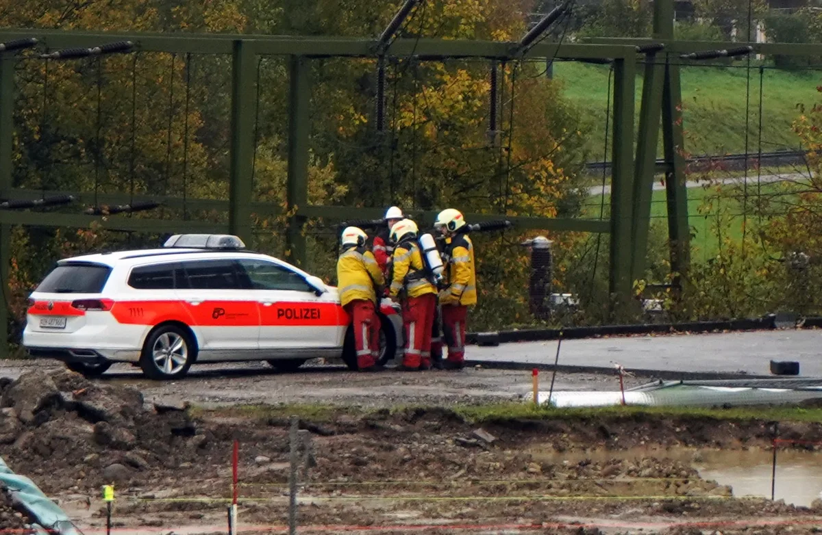 Die Einsatzkräfte der Feuerwehr besprechen sich. Feuerwehrleute vor einem Polizeiauto.