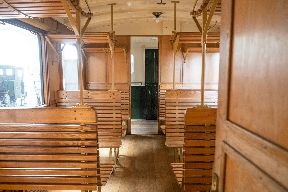 Im Sitzbereich haben bis zu 30 Leute Platz. Man sieht das Innere des Dampftriebwagens mit Holzbänken und Gepäckablagen.