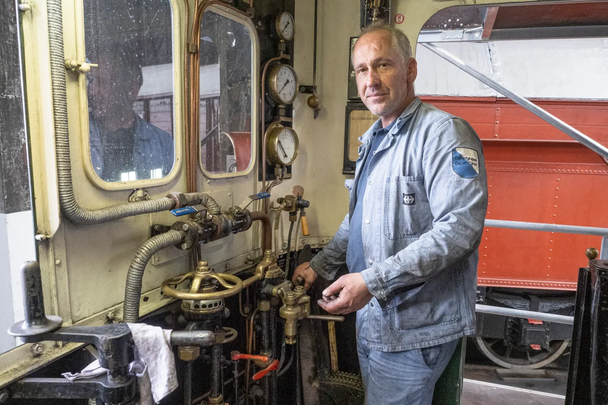 Sein Führerstand ist auf Einmannbetrieb ausgelegt – so konnte der Heizer eingespart werden. Man sieht einen Mann, der in einem alten Führerstand steht.