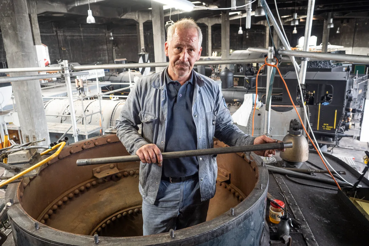 So sehen die Rohre, die in den Kessel kommen, in ihrer ganzen Länge aus. Man sieht einen Mann, der oben in einem Kessel steht und ein Rohr in den Händen hält.