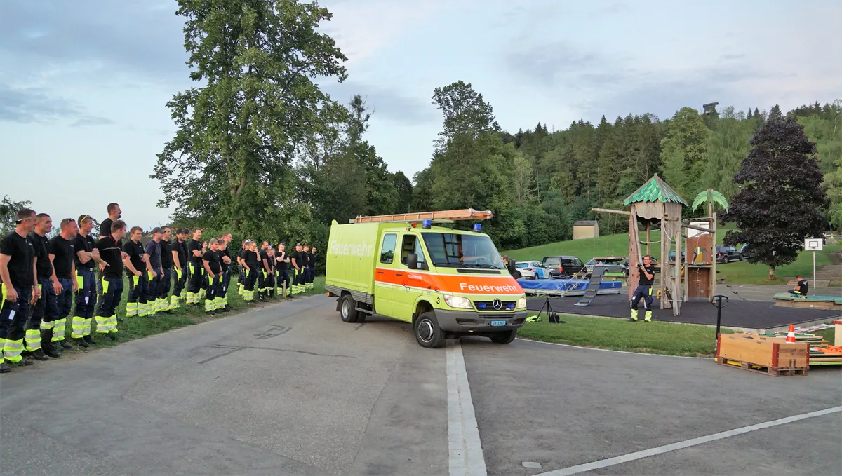 Feuerwehrangehörige stehen Spalier für Feuerwehrauto.