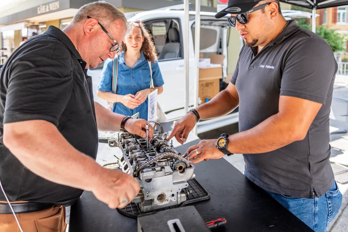 Bei der Top Garage Fischenthal AG konnte man selbst Hand bei einem Motor anlegen. Stefan versucht sich beim Kerzenwechsel. Zwei Männer wechseln eine Kerze.