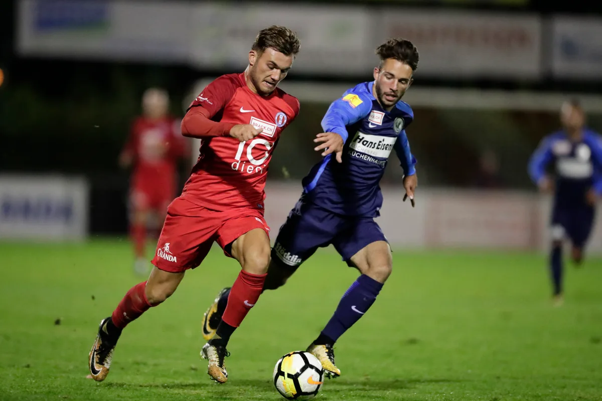 Zwei Männer in Fussballtrikots kämpfen um den Ball. 