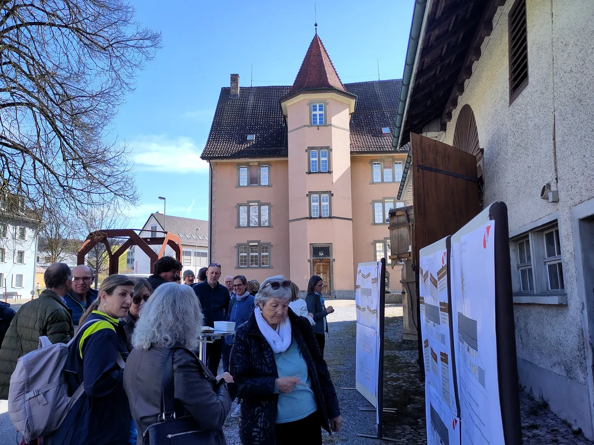 Man sieht Personen, die vor Stellwänden diskutieren.