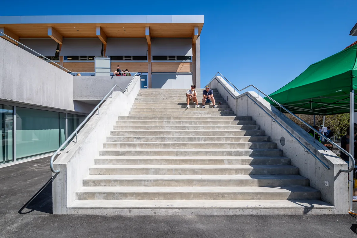 Die grosszügige Aussenraumgestaltung und die imposante Treppe bieten viel Platz in den Pausen. Eine grosse Treppe vor einem Schulhaus.