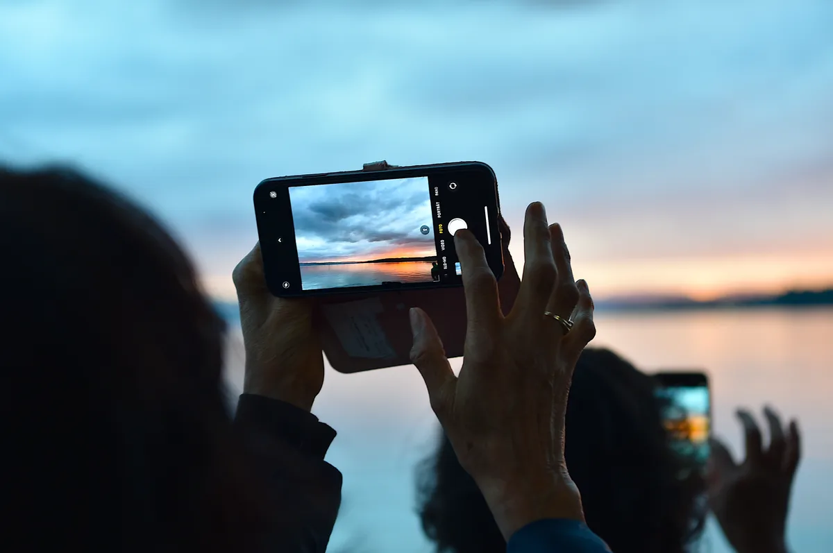 Andere hatten am Samstag auch das Auge für romantische Szenen. Man sieht eine Person, die mit dem Handy den Sonnenuntergang fotografiert.