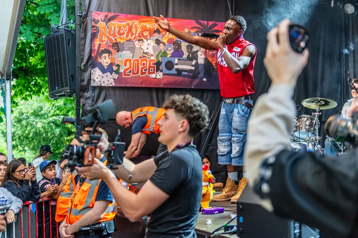 Der Auftritt von Rody sorgte für ein gewisses Medienecho. Vor einer Bühne auf der ein Rapper steht Sicherheitspersonal und ein Kameramann.