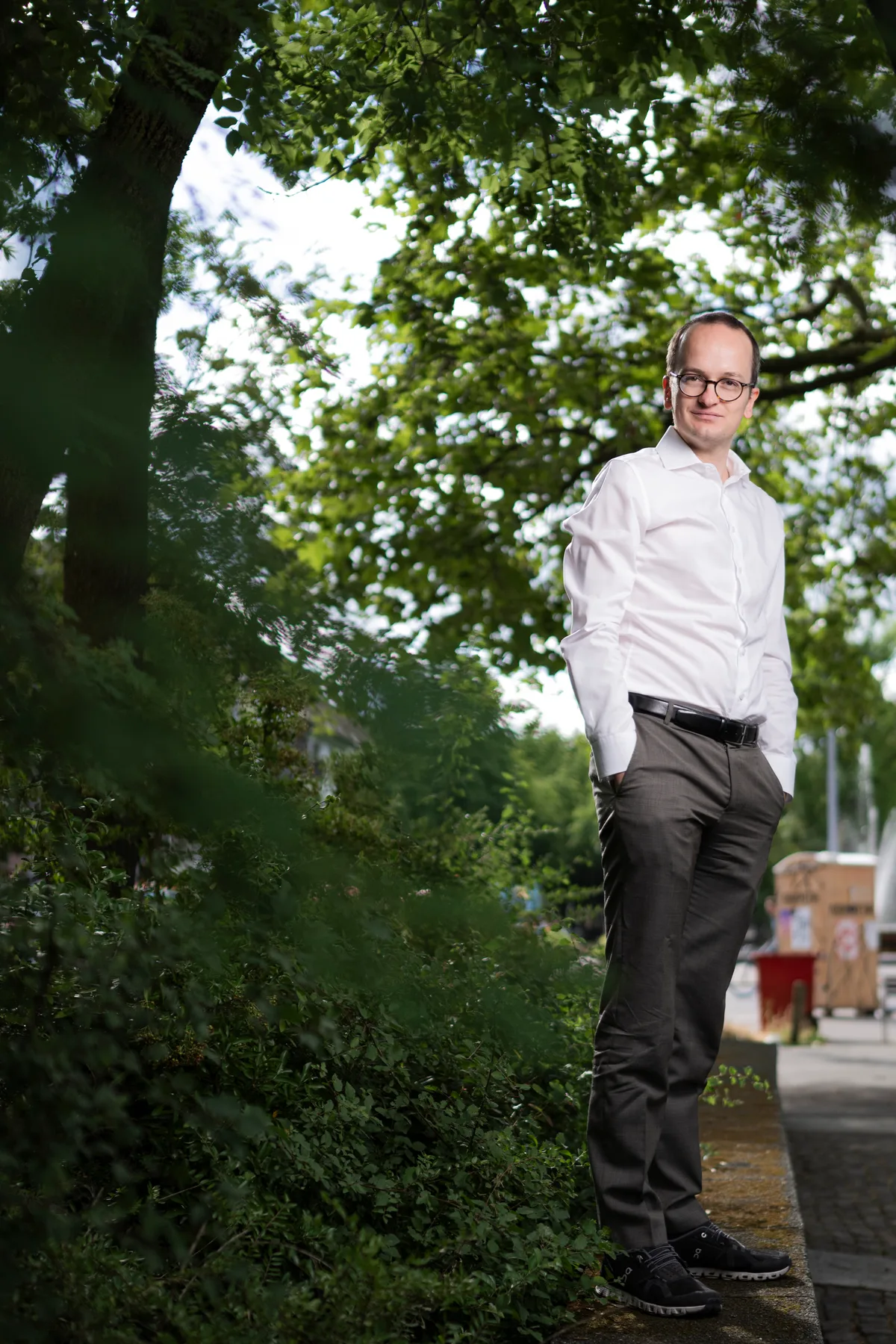 Man sieht einen Politiker mit weissem Hemd und anthrazitfarbener Hose, der in einem Park steht.
