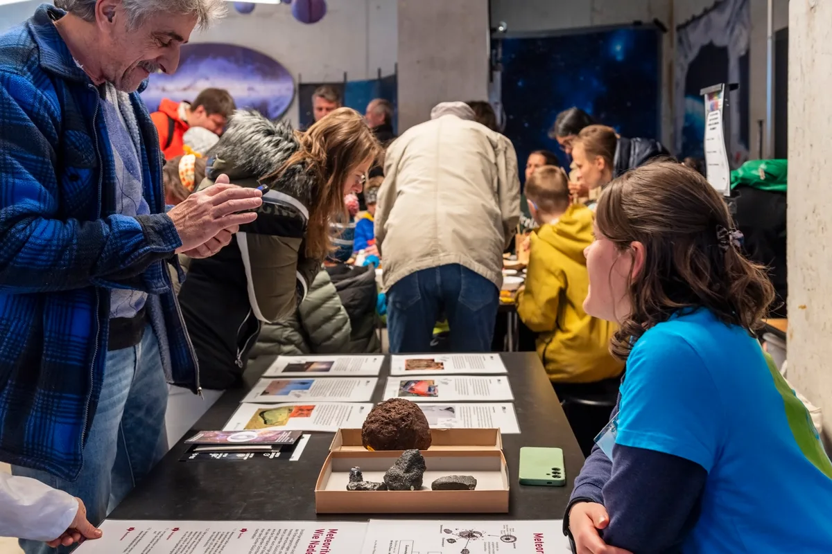 Eine Frau sitzt hinter einem Stück Stein: Es ist ein Meteorit.