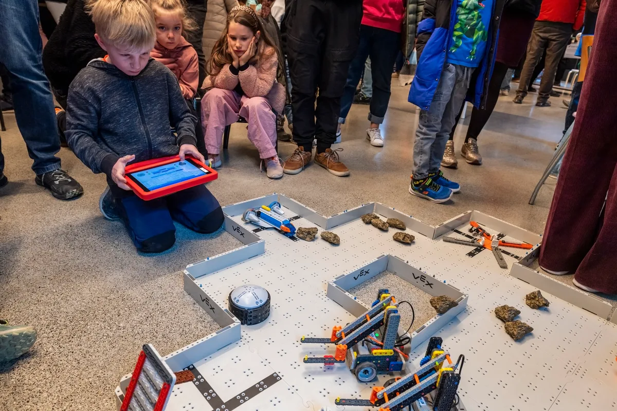 Man sieht einen Jungen, der mit einem Tablet einen Marsroboter steuert.