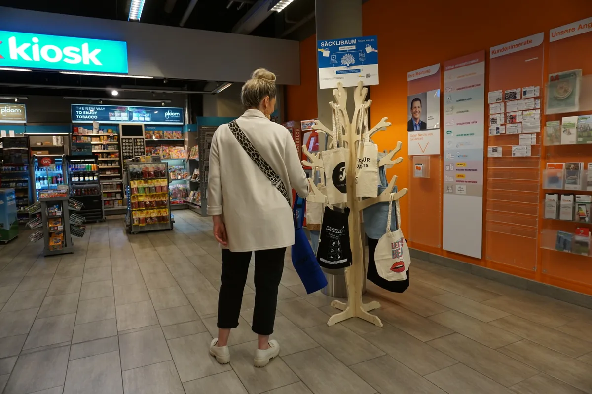 Eine Person steht neben dem Säckli-Baum und bedient sich.