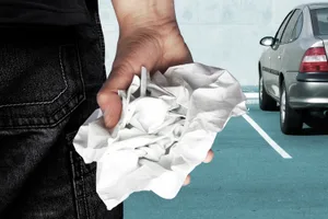 Man sieht eine Hand in Grossaufname und ein Auto auf einem Parkplatz Man sieht eine Hand in Grossaufname und ein Auto auf einem Parkplatz