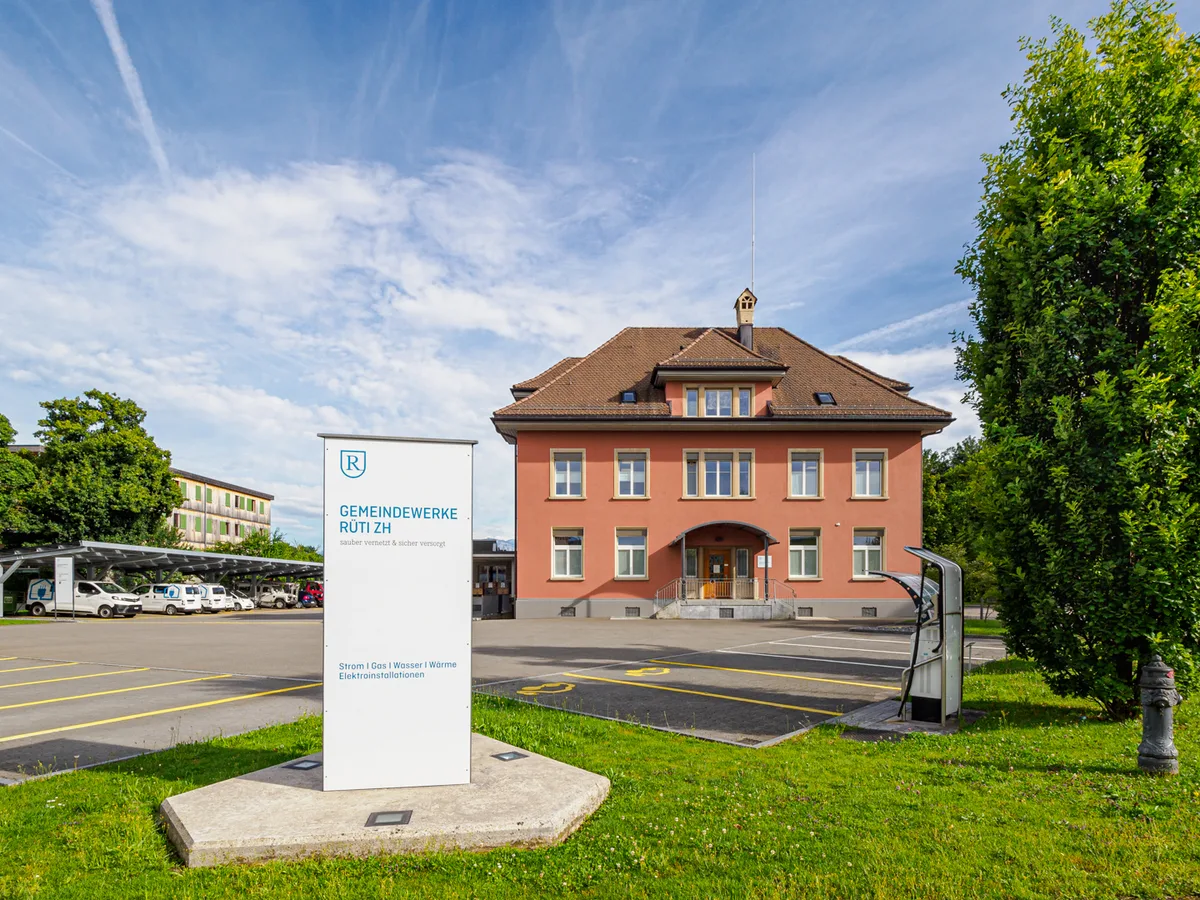 Ein rotes Haus und eine Tafel davor.