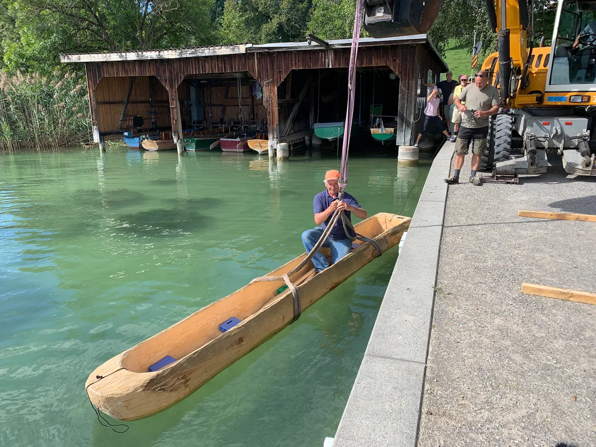 Am 16.9.2023 wird in der Schiffländi Seegräben der erste Einbaum eingewassert, zudem können Kinder an verschiedenen Posten Pfahlbautechniken wie Töpfern, Steinbeil schlagen oder Silexklingen herstellen üben; ausserdem ist bei der Messikommer-Eiche der Fundort des 1957 geborgenen Einbaums vorgestellt worden sowie die Technik des Torfstechens; im Bild: Hans Glauser, der den Stamm des Einbaums geschlagen hat, löst die Transportschlaufe